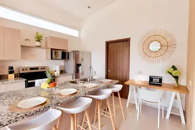 a kitchen with a large island with white stools at Modern 2BR Condo - minutes from Jaco Beach - PRIME location in Jacó