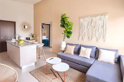 a living room with a blue couch and a kitchen at Modern 2BR Condo - minutes from Jaco Beach - PRIME location in Jacó