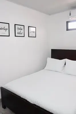 a bedroom with a white bed with three pictures on the wall at Airport SJO Residence Cars4Rent 