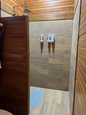 a shower in a bathroom with wood paneling at Cabañas Don Ramiro in Colonia Dos Ríos
