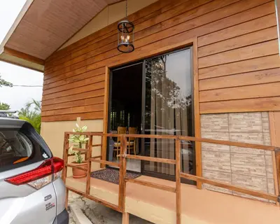 a house with a balcony with a car parked outside at Bungalows Las Iguanas Arenal Volcano in Fortuna