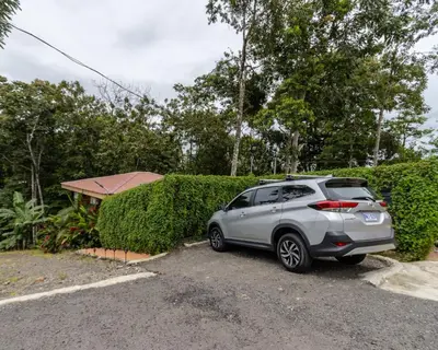 a car parked in a parking lot next to a hedge at Bungalows Las Iguanas Arenal Volcano in Fortuna