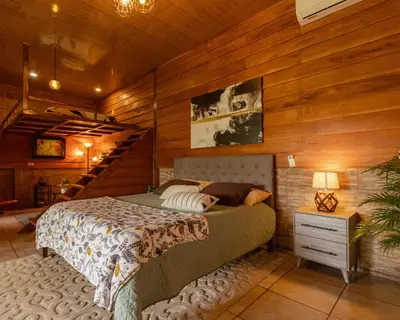 a bedroom with a bed in a room with wooden walls at Bungalows Las Iguanas Arenal Volcano in Fortuna