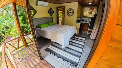 a bedroom with a bed with green pillows on it at Bungalows Las Iguanas Arenal Volcano in Fortuna