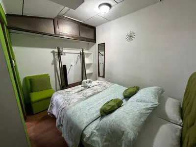 a bedroom with two beds and a green chair at Apartment 10 minutes by the SJO airport - in Alajuela City