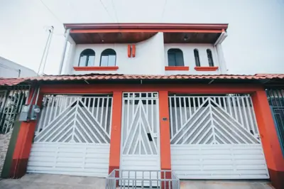 a building with white doors and red accents at Apartment 10 minutes by the SJO airport - in Alajuela City