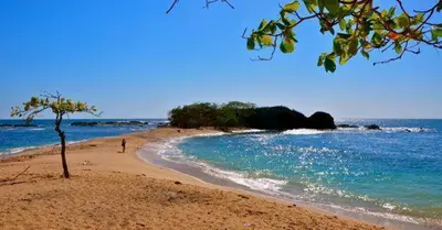 a person walking on a sandy beach near the ocean at Cabinas surf Arribadas in Playa Ostional