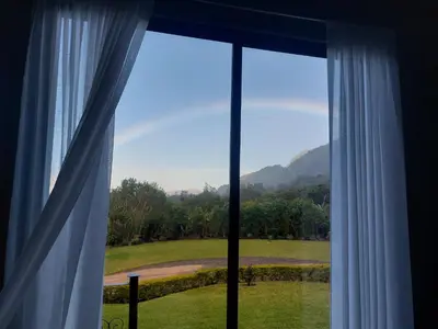 a window with a view of a field and mountains at Villa Golondrina Cabaña rodeada de Naturaleza in Monteverde Costa Rica