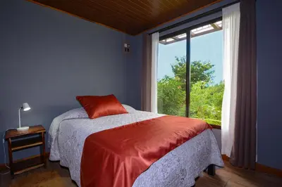 a bedroom with a bed and a large window at Villa Golondrina Cabaña rodeada de Naturaleza in Monteverde Costa Rica