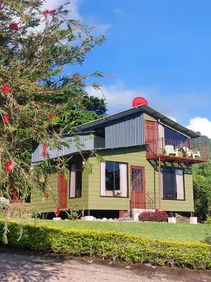 a green house with a black roof at Villa Golondrina Cabaña rodeada de Naturaleza in Monteverde Costa Rica