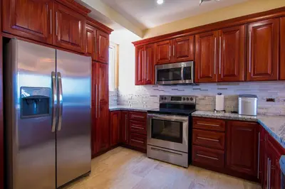 a kitchen with wooden cabinets and a stainless steel refrigerator at Break Water Point Penthouse 7th Floor in Jacó