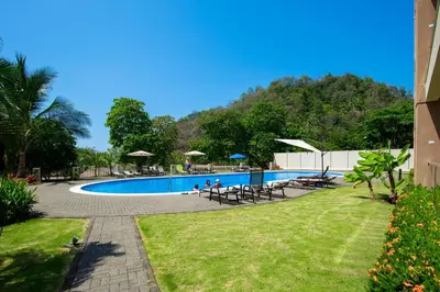 a swimming pool with chairs and umbrellas in a resort at Break Water Point Penthouse 7th Floor in Jacó