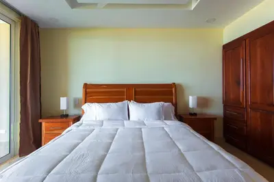 a bedroom with a large white bed with wooden furniture at Break Water Point Penthouse 7th Floor in Jacó