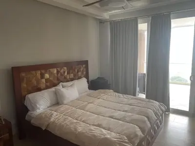 a bedroom with a large bed with a large window at Break Water Point Penthouse 7th Floor in Jacó