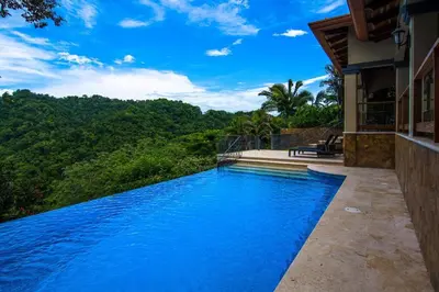 a swimming pool in front of a house with trees at Casa Sol in Herradura