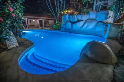 a swimming pool at night with a couch in it at Hotel El Jardin in Montezuma