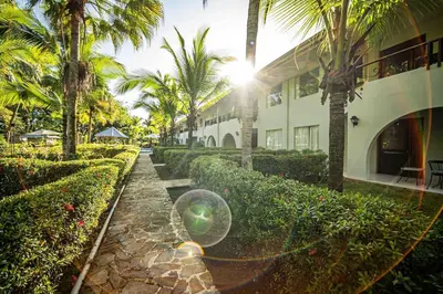 a building with palm trees and a stone walkway at Lovely Condo near monkey habitat and beach in Quepos