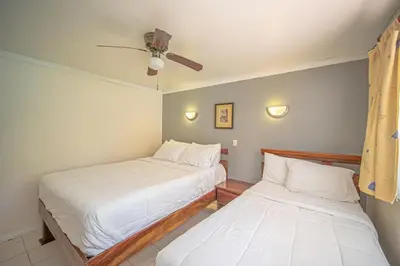 two beds in a room with white sheets at Lovely Condo near monkey habitat and beach in Quepos