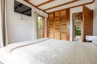 a bedroom with a large bed and a television at Villa Fruta del Cielo in Uvita