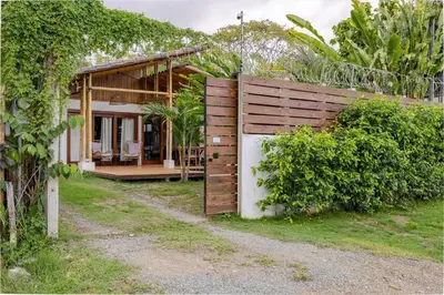 a house with a wooden fence and a yard at Villa Fruta del Cielo in Uvita