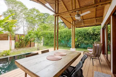 an outdoor dining area with a wooden table and chairs at Villa Fruta del Cielo in Uvita