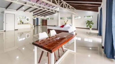a bedroom with a bed and a wooden table at The Babylon Suite Tortuguero in Tortuguero