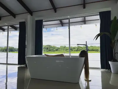 a white bath tub in a room with windows at The Babylon Suite Tortuguero in Tortuguero