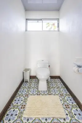 a bathroom with a toilet and a rug on the floor at The Babylon Suite Tortuguero in Tortuguero