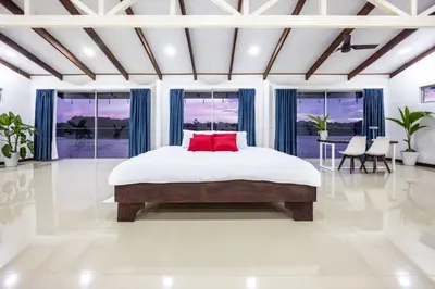 a bedroom with a large bed with a red pillow at The Babylon Suite Tortuguero in Tortuguero