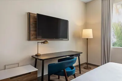 a room with a desk with a tv and a blue chair at Fairfield by Marriott San Jose Airport Alajuela in Alajuela City