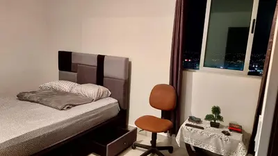 a bedroom with a bed and a chair and a window at Altamira Cozy apartment with amazing views in Santo Domingo