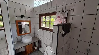 a bathroom with a toilet and a sink and a window at Casa Hibiscus in Ojochal