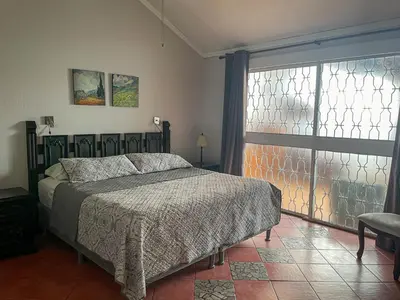 a bedroom with a bed and a large window at Hotel Ave del Paraíso in San José