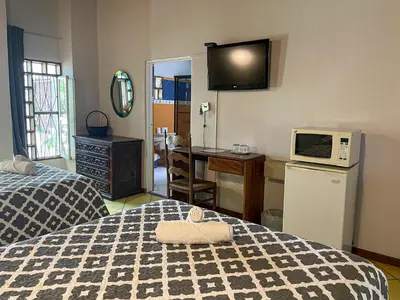 a room with a bed and a kitchen with a microwave at Hotel Ave del Paraíso in San José