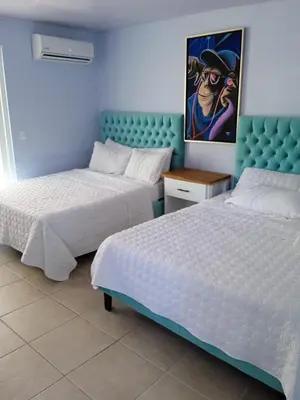 a bedroom with two beds and a painting on the wall at Hotel Mono Azul in Quepos