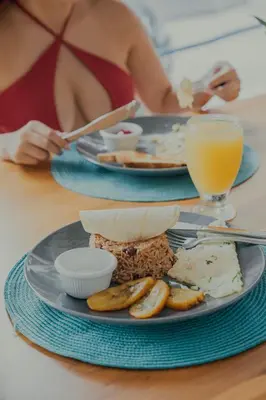a table with two plates of food and a glass of orange juice at Hotel Mono Azul in Quepos