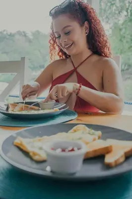 a woman sitting at a table with a plate of food at Hotel Mono Azul in Quepos