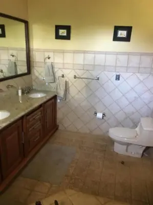 a bathroom with a toilet and two sinks and a mirror at 3 Bedroom Villa in Hacienda Pinilla in Tamarindo