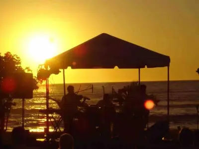 a group of people sitting at a table on the beach at sunset at 3 Bedroom Villa in Hacienda Pinilla in Tamarindo