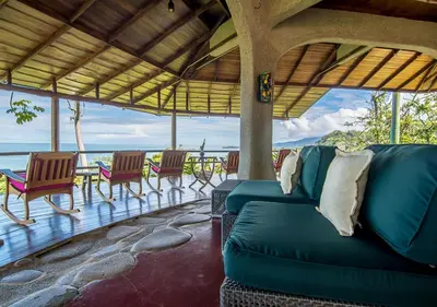 a living room with a couch and chairs on a porch at La Cusinga Lodge in Uvita