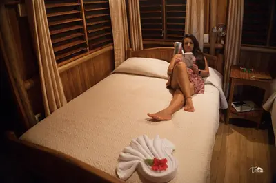 a woman sitting on a bed talking on a phone at La Cusinga Lodge in Uvita