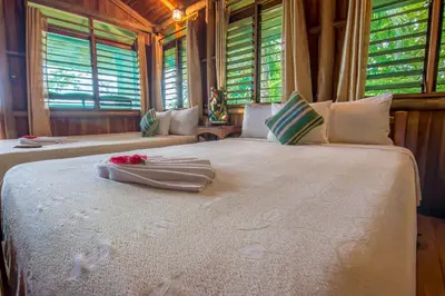 a bedroom with two beds with flowers on top of it at La Cusinga Lodge in Uvita