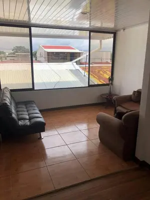 a living room with two couches and a large window at Pinky’s Place Airport, Full Equipment. in Alajuela City