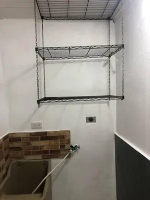 a bathroom with a urinal and a shelf on the wall at Pinky’s Place Airport, Full Equipment. in Alajuela City