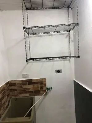 a bathroom with a urinal and a shelf on the wall at Pinky’s Place Airport, Full Equipment. in Alajuela City