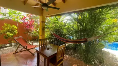 a porch with a hammock and a table and chairs at The Inner Light Yoga Lodge in Sámara