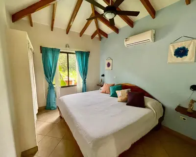 a bedroom with a bed with blue walls and a ceiling at The Inner Light Yoga Lodge in Sámara