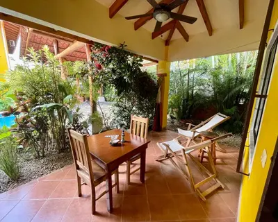 a porch with a wooden table and chairs on it at The Inner Light Yoga Lodge in Sámara