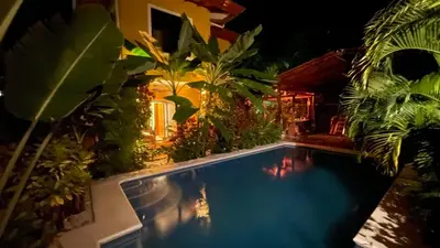 a swimming pool in a garden at night at The Inner Light Yoga Lodge in Sámara