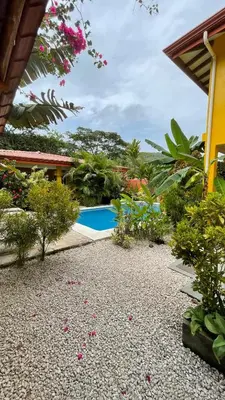 a resort yard with a swimming pool and flowers at The Inner Light Yoga Lodge in Sámara